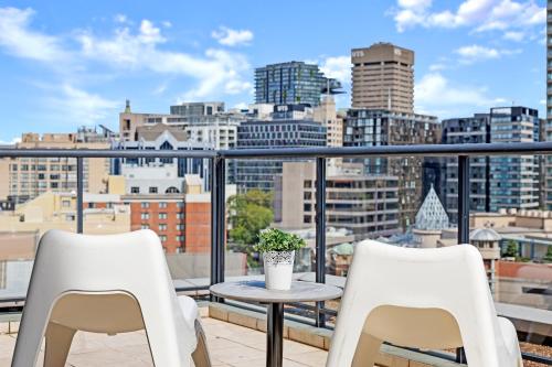 a balcony with two chairs and a table and a city at KOZYGURU | Sydney CBD | Lovely 2 Bedroom APT with Amazing City View in Sydney