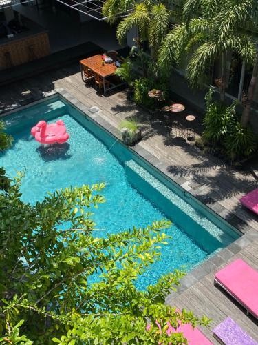 a swimming pool with a pink flamingo in the water at Lushy Hostel Canggu in Canggu