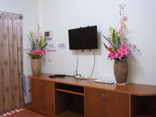 a room with two vases with flowers and a tv at Pru Valley Thaley Tai Resort in Ban Don Phlap (1)