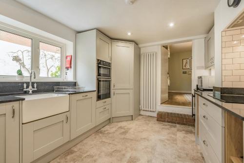 a kitchen with white cabinets and a sink at Riverside House in Fordingbridge