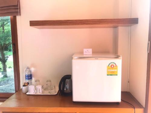 a white refrigerator sitting on a shelf in a kitchen at Pru Valley Thaley Tai Resort in Ban Don Phlap (1)