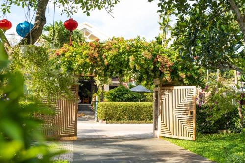 einen Zugang zu einem Garten mit einem hölzernen Bogen mit Blumen in der Unterkunft Chi Thanh Villa in Hoi An