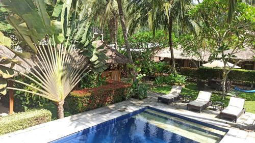 a pool in a garden with two chairs and trees at Mama Bella's Retreat in Senggigi