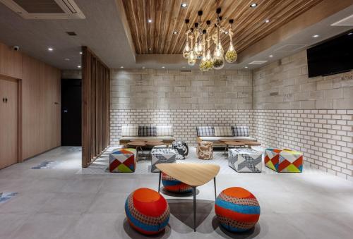 a lobby with tables and chairs and a television at Smile Hotel Okayama in Okayama