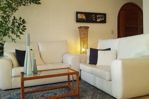 a living room with two white couches and a table at Cancun condo en la playa de Puerto Juarez in Cancún