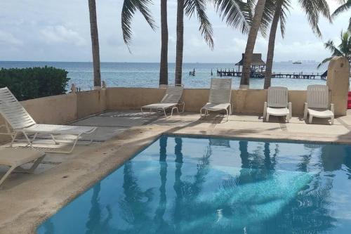 a swimming pool with chairs and the ocean in the background at A la Orilla del mar Puerto Juarez Cancun in Cancún