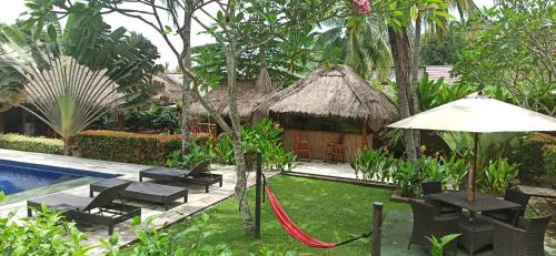 a garden with a pool and a resort with a hammock at Mama Bella's Retreat in Senggigi