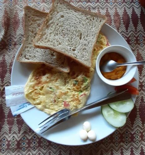 a plate of food with eggs and toast and a cup of sauce at Mama Bella's Retreat in Senggigi 