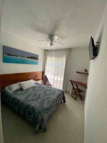 a bedroom with a bed, chair and a window at Gran Jaguar Hotel in Bacalar