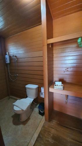 La salle de bains est pourvue de toilettes et d'un mur en bois. dans l'établissement Inpai Resort อินปายรีสอร์ท, 