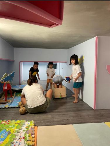 a man sitting on the floor in a room with three children at 睡海邊包棟民宿 sleep on beach B&B in Suao