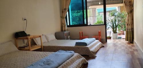 a room with three beds and a window at Mai Homestay in Sầm Sơn