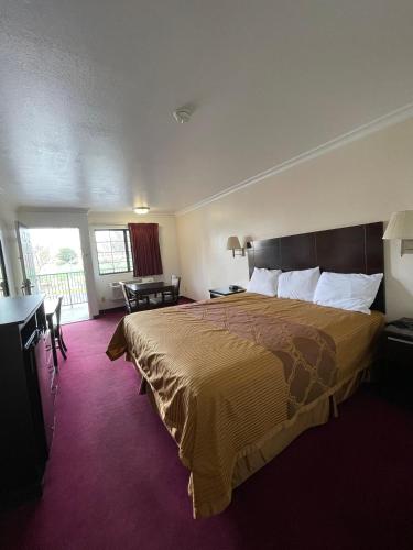 a hotel room with a large bed and a desk at Chino Motel in Chino