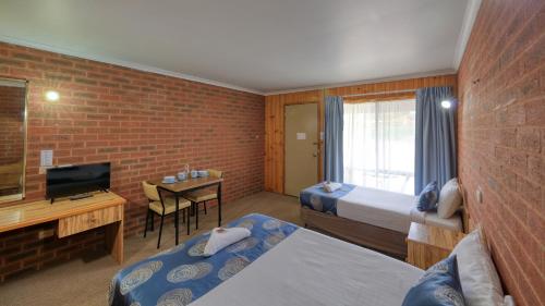 una camera d'albergo con due letti e una scrivania con televisore di Barham Riverland Motel a Barham