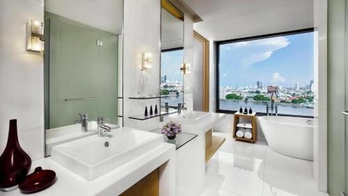 a bathroom with two sinks and a large window at Avani Plus Riverside Bangkok Hotel in Bangkok