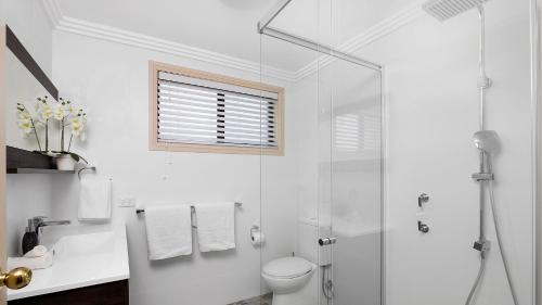 a white bathroom with a shower and a toilet at Karinya at Little Beach Upstairs in Nelson Bay