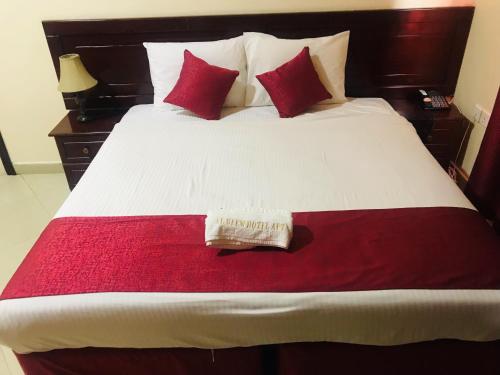 a bed with red and white sheets and red pillows at Al Reem Hotel Apartments in Sharjah