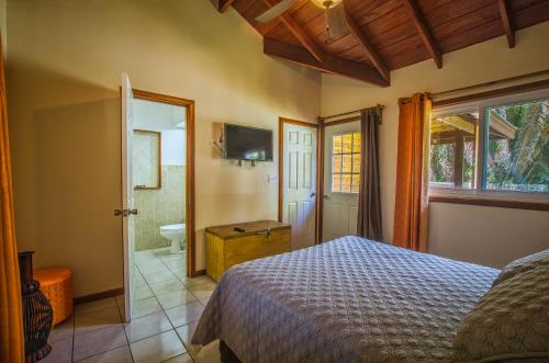 a bedroom with a bed and a bathroom at Relaxing Tropical Cabin in Roatan