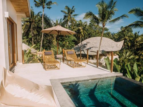 a resort pool with chairs and an umbrella at Neano Escape in Candidasa