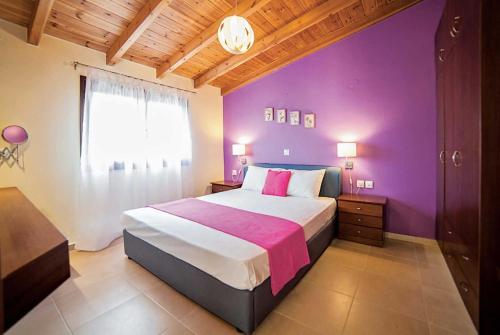 een slaapkamer met paarse muren en een groot bed bij Mandarin Platanias Crete in Plataniás