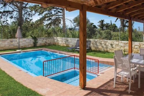 een zwembad in een tuin met een tafel en stoelen bij Mandarin Platanias Crete in Plataniás