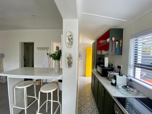 una cocina con encimera blanca y taburetes. en Walmer Cottage - Cute & Pet friendly, en Ciudad del Cabo