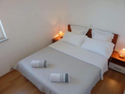 a bedroom with a white bed with two pillows on it at Apartments Mlikota in Zaton