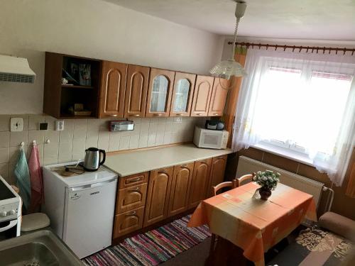 a kitchen with wooden cabinets and a table and a sink at Apartmán Na Kopečku in Modrava