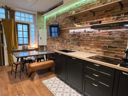 une cuisine avec des armoires noires et un mur en briques dans l'établissement GOOD VIBES Luxurious Loft in Paris 11th, with AC & table football, à Paris