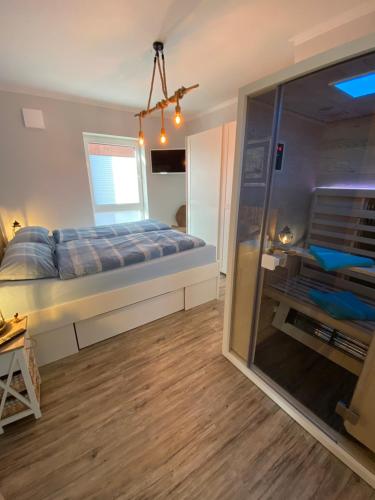1 dormitorio con 1 cama y puerta corredera de cristal en Ferienwohnung Nordseenah, en Esens