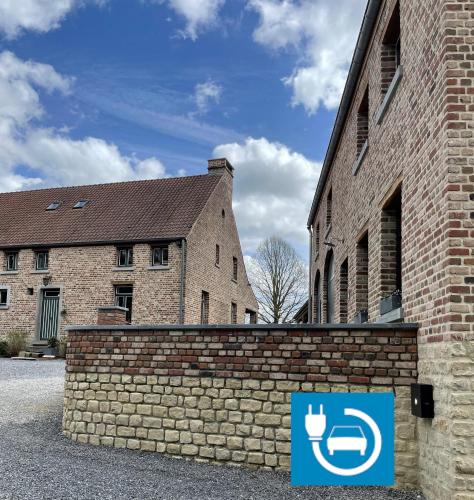 a brick wall next to a building with a sign on it at Les Chanterolles in Chaumont-Gistoux