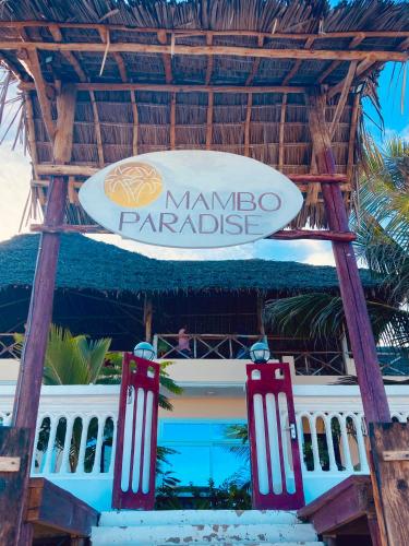 a sign in front of a building with a surfboard at Mambo Paradise in Matemwe