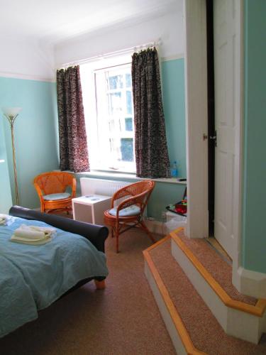 a bedroom with a bed and chairs and a window at Weston Manor in Freshwater