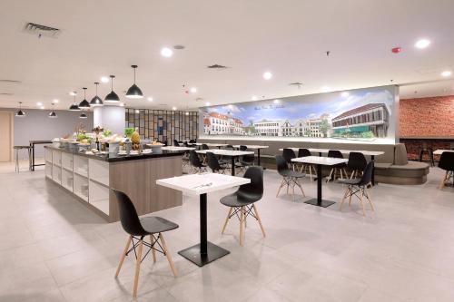 un restaurant avec des tables, des chaises et un comptoir dans l'établissement Azana Style Hotel Bandara Jakarta, à Tangerang