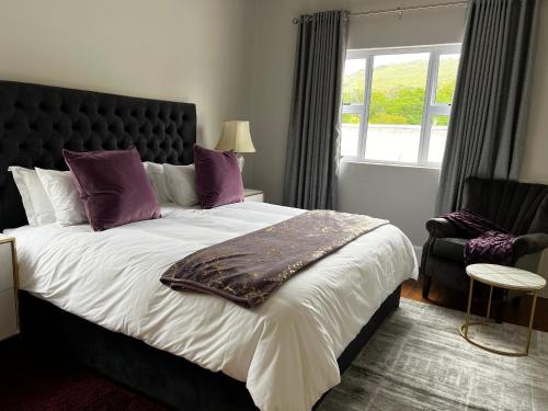 Un dormitorio con una cama grande con almohadas moradas y una ventana en Ndaba Golf Lodge & Hello Beautiful Day Spa, en Queenstown