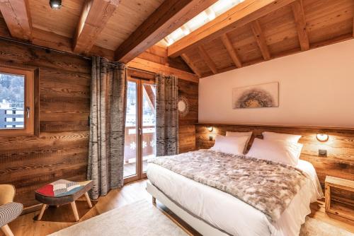 a bedroom with a bed in a room with wooden walls at Chalet Galibier in Saint-Chaffrey