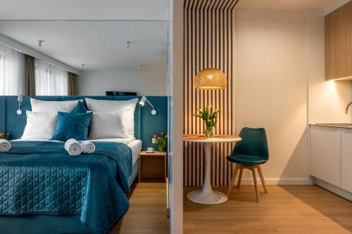 a bedroom with a blue bed and a green chair at InPoint Central Apartments in Kraków
