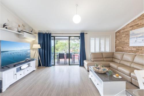 a living room with a couch and a tv at Coastal Paradise at Fore Dek 3, 17 Soldiers Point Road - water views, linen, Wi-Fi, Air Con in Soldiers Point