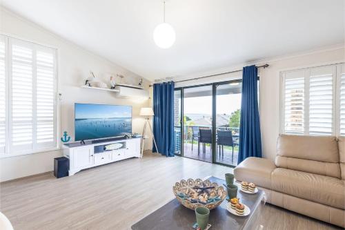 a living room with a couch and a tv at Coastal Paradise at Fore Dek 3, 17 Soldiers Point Road - water views, linen, Wi-Fi, Air Con in Soldiers Point