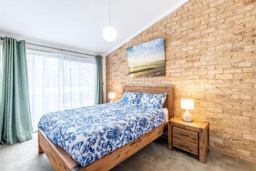 a bedroom with a bed and a brick wall at Coastal Paradise at Fore Dek 3, 17 Soldiers Point Road - water views, linen, Wi-Fi, Air Con in Soldiers Point