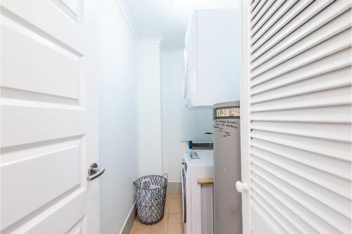 a small kitchen with white cabinets and a refrigerator at Coastal Paradise at Fore Dek 3, 17 Soldiers Point Road - water views, linen, Wi-Fi, Air Con in Soldiers Point