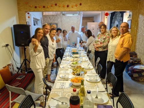 a group of people standing around a long table with food at אשראם בכרמל - המקום של אורי in Dāliyat el Karmil