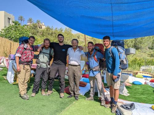 a group of men standing under a blue umbrella at אשראם בכרמל - המקום של אורי in Dāliyat el Karmil