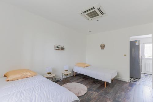 a white bedroom with two beds and a window at Le Vexin in Gisors