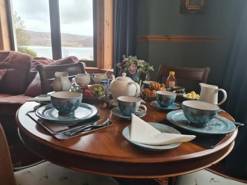 a wooden table with cups and plates on top of it at Creag-Ard Bed & Breakfast in Dundonnell