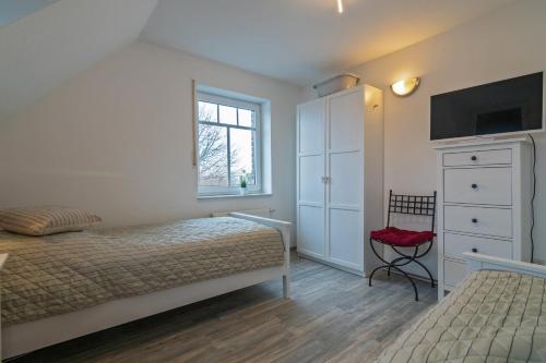 Un dormitorio con una cama y una cómoda y una ventana. en Leuchtturm, en Dornumergrode