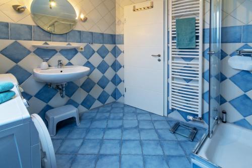 Un baño azul y blanco con lavabo y ducha. en Leuchtturm, en Dornumergrode