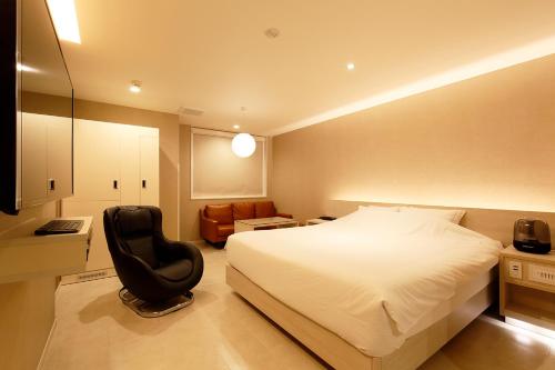 a hotel room with a bed and a chair at KNOWS HOTEL in Numazu