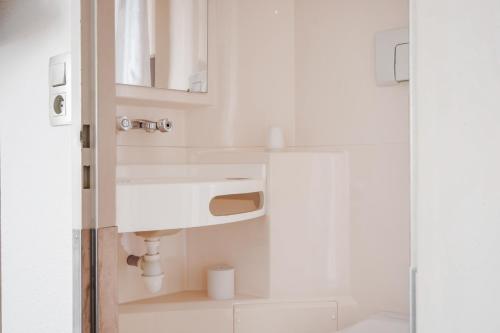 een witte badkamer met een wastafel en een douche bij Premiere Classe Lyon Est - Bron Eurexpo in Décines-Charpieu