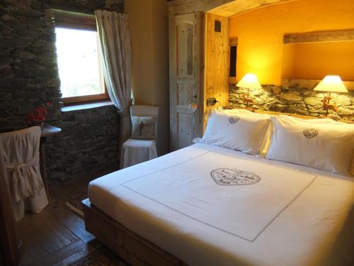 a bedroom with a large bed with white sheets at La Luge D'Antan Maison d'Hôtes & SPA in Brusson